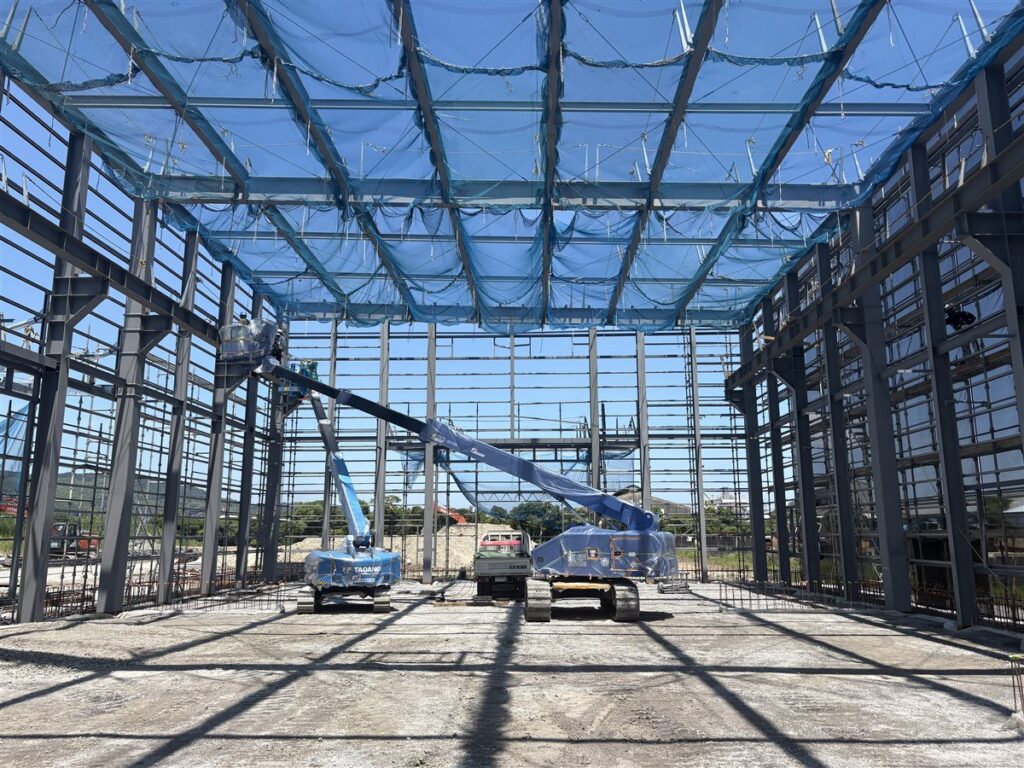 棟上げ作業中の鉄骨工場内部と高所作業車